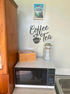 a microwave on a counter with a sign that reads coffee and tea at Cameo B&B in Matamata
