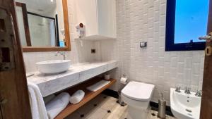 a white bathroom with a sink and a toilet at Le Flâneur Boutique Hotel in Pergamino