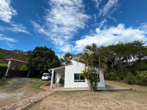 a white house with a palm tree in front of it at Finca El Balmoral in Tocaima