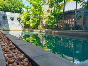 a swimming pool in front of a house with palm trees at Bou Savy Guesthouse in Siem Reap