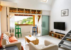 a living room with a couch and a tv at Le Palmier Bleu, Spacious Duplex with Pool in Schœlcher