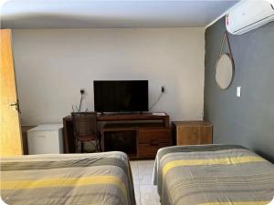 a room with two beds and a television in a room at Quarto privativo Pousada Luna in Fernando de Noronha