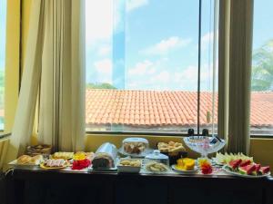 a buffet of food on a table in front of a window at Quarto privativo Pousada Luna in Fernando de Noronha