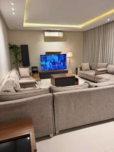a living room with two couches and a flat screen tv at شاليهات دبليو العمارية W Chalet in Al ‘Ammārīyah