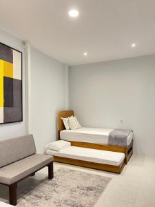 two beds in a room with a chair and a couch at Kuraya Urban Space in Surabaya