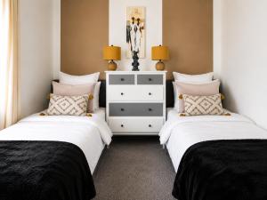 a bedroom with two beds and a dresser at Walk to Town, Parking, Family Home, drive to beach in Bridgend