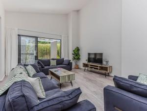 a living room with blue couches and a tv at Longboard Coastal Retreat in Kingscliff