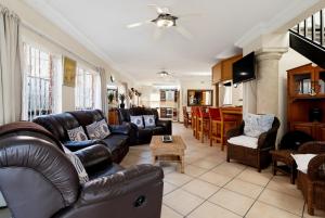 a living room with leather couches and a kitchen at Palm View in Ballito