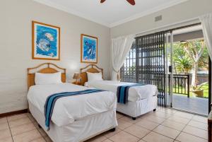 two beds in a room with a balcony at Palm View in Ballito +26 photos