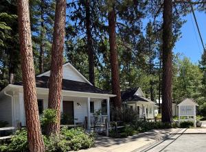 a white house with trees in front of it at The Cottages at Bigfork in Bigfork