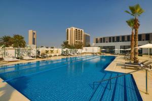 a large swimming pool with palm trees and buildings at Sheraton Bahrain Hotel in Manama