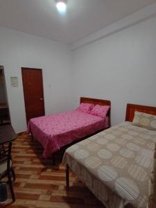 two beds in a room with pink sheets at Hospedaje Miramar in Máncora +6 photos