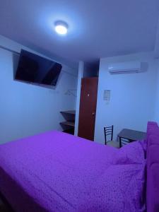 a bedroom with a purple bed and a tv at Hospedaje Miramar in Máncora