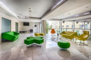 a lobby with green and yellow chairs and tables at Holiday Inn Sittingbourne by IHG in Sittingbourne