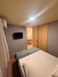 a bedroom with a bed and a tv on the wall at Sky Luxury Suites in Bucaramanga