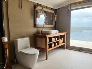 a bathroom with a toilet and a sink and a mirror at The Agung & Sunset Tent by BaliSuperHost in Nusa Penida