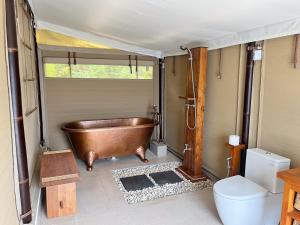 a bathroom with a copper tub and a toilet at The Agung & Sunset Tent by BaliSuperHost in Nusa Penida +36 photos