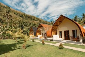 a house with a round roof and a grass yard at The Kaci Penida By Bali Cabin in Nusa Penida