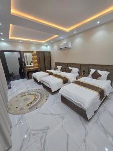 a hotel room with three beds in a large room at شالية ورد in Rayyis