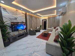 a living room with a tv and a couch at شالية ورد in Rayyis