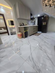 a large kitchen with white marble floors and a counter at شالية ورد in Rayyis