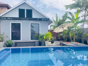 a villa with a swimming pool in front of a house at Sanctuary Homestay Battambang in Phumĭ Don Téav