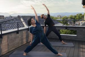 a man and a woman doing yoga on a roof at Sowaka in Kyoto