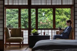 a man sitting in a window reading a book at Sowaka in Kyoto