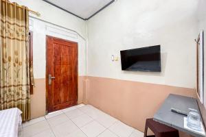 a room with a door and a tv on the wall at Homestay E Rahayu Anyer RedPartner in Serang
