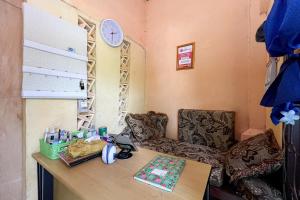 a room with a desk and two chairs and a clock at Homestay E Rahayu Anyer RedPartner in Serang