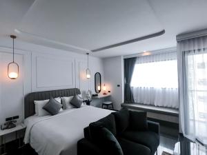 a bedroom with a bed and a chair and a window at Ratri Hotel Phuket Old Town in Phuket