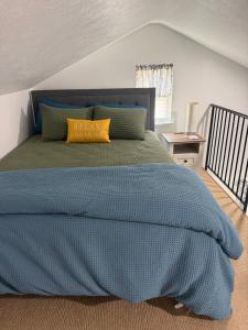 a bedroom with a bed with a blue comforter and yellow pillows at Cozy Creek Retreat in Waterford