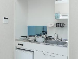 a kitchen with a sink and two pots and pans at ホテルステイ伊万里 in Imari