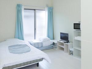 a bedroom with a bed and a tv and a window at ホテルステイ伊万里 in Imari