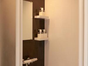 a mirror in a bathroom with two soap dispensers at ホテルステイ伊万里 in Imari