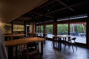a restaurant with wooden tables and chairs and windows at いっぺ The Sake Ryokan in Kyonan