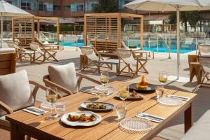 a wooden table with plates of food and glasses of wine at Meliá Madrid Barajas in Madrid