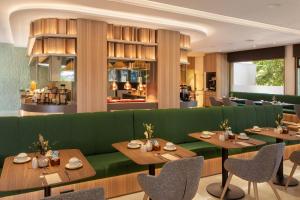 a restaurant with a green couch and tables and chairs at Meliá Madrid Barajas in Madrid