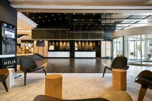 a lobby with chairs and tables in a building at Meliá Madrid Barajas in Madrid