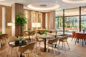 a restaurant with tables and chairs and windows at Meliá Madrid Barajas in Madrid +65 photos