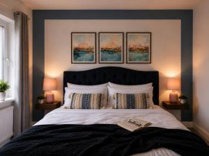 a bedroom with a large bed with three paintings on the wall at Walk to Town, Parking, Family Home, drive to beach in Bridgend