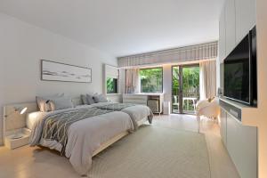 a white bedroom with a large bed and a television at Tree Villa Bangkok in Bangkok