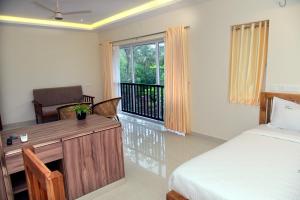 a bedroom with a bed and a desk and a window at Villa Varkala in Varkala