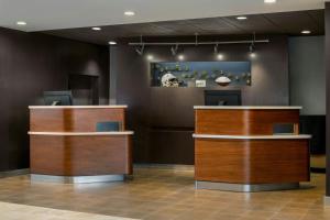 a lobby with two wooden counters and a painting on the wall at Courtyard by Marriott Pittsburgh Airport in Coraopolis