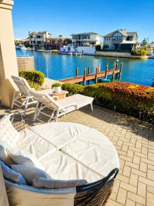 a bed and chairs on a patio next to the water at Apollo Stayz Luxury Waterfront Home 57 - Pool - Spa - Jetty in Mandurah