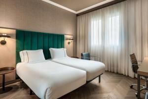 a hotel room with a large bed and a green headboard at AC Hotel Bologna by Marriott in Bologna +106 photos