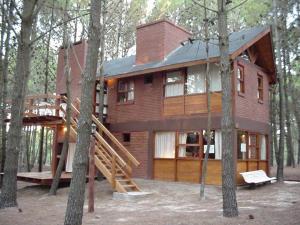 a house in the woods with a tree at Cabañas El Ocio in Mar de las Pampas