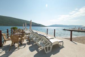 a group of chairs and tables on a dock near the water at Apartments Batricevic in Herceg-Novi