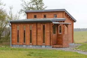 eine Holzhütte auf einem Grasfeld in der Unterkunft Chalets am National Park Eifel in Schleiden