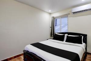 a bedroom with a black and white bed and a window at Hotel O Satyam Junction Seethammadhara in Visakhapatnam